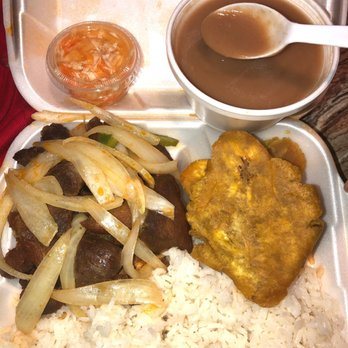 A takeout plate with white rice, meat with onions, fried plantain and sides