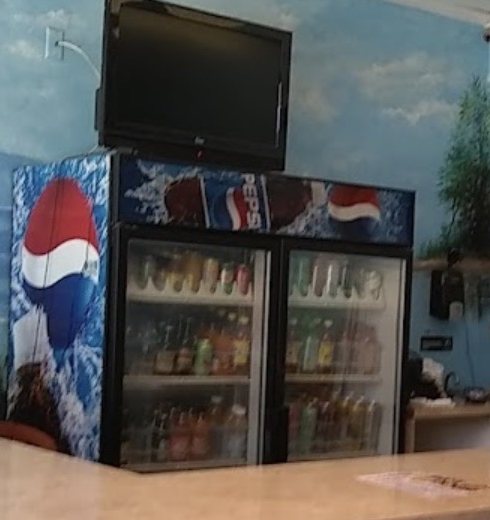 Inside J J Gourmet: a drinks cooler in front of a painted sky and ocean mural